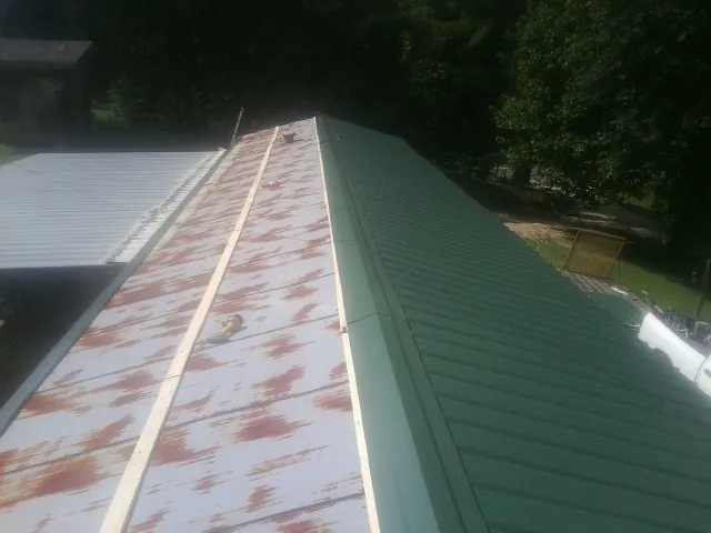 Old rusted panels beside newly installed green metal roofing — Wind Damage Roof Repair by Roofing Brothers in Clemson