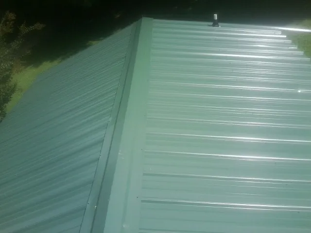 New green metal panels meeting at the ridge of a roof — Flat Roof Repair work by our crew in Clemson