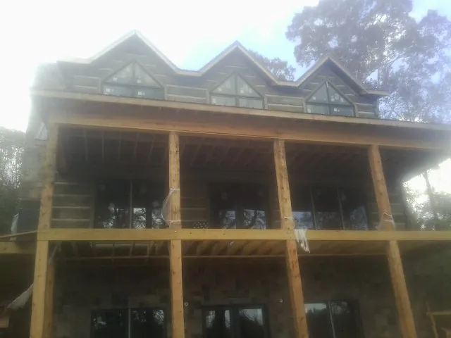 Dormers and porch framing on a large log home under construction — Roof Coating work by our crew in Clemson