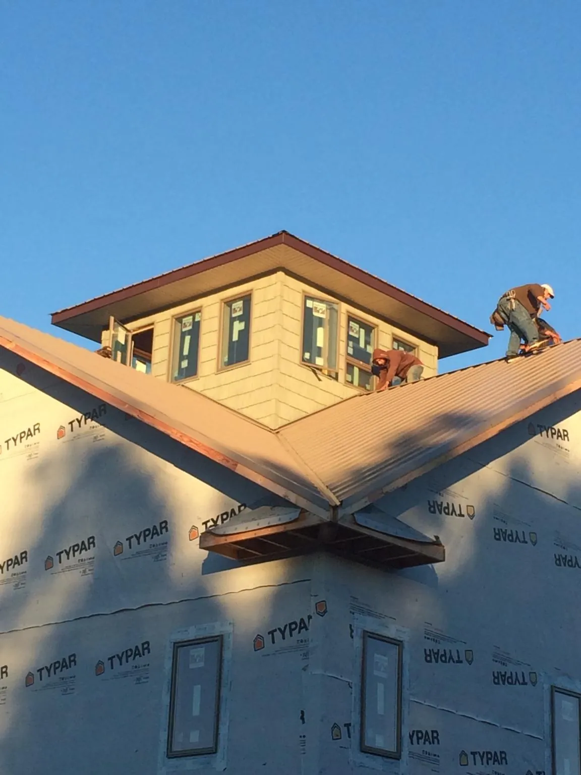 Roofers working around a rooftop cupola on a new metal roof at sunset — Roof Waterproofing in Clemson by Roofing Brothers